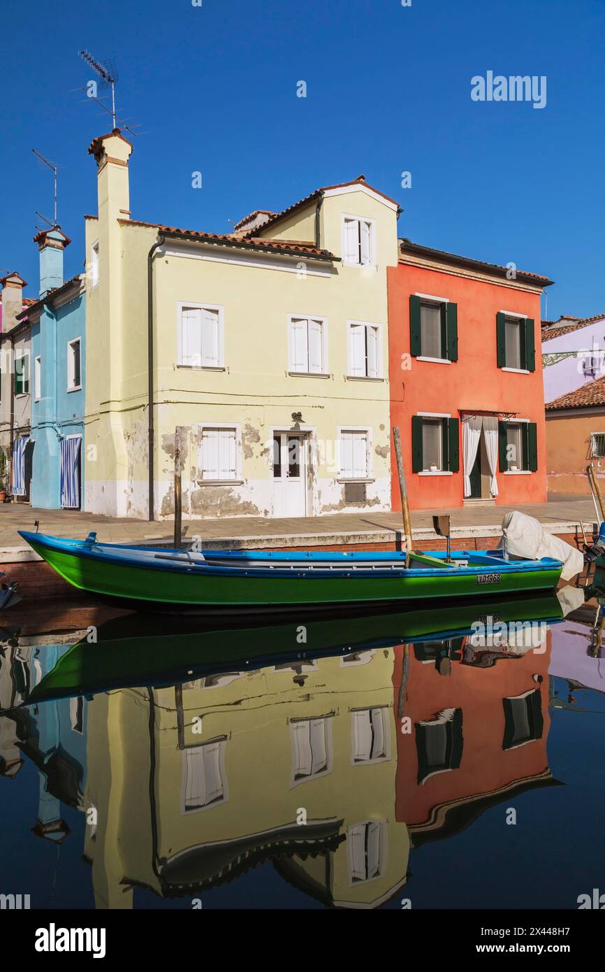 Bateau amarré vert et bleu sur le canal bordé de maisons en stuc jaune et rouge, île de Burano, lagune vénitienne, Venise, Vénétie, Italie Banque D'Images
