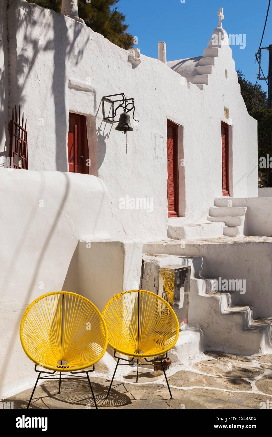 Deux chaises jaunes de conception moderne devant le bâtiment avec petite chapelle, Mykonos Town, Mykonos Island, Grèce Banque D'Images