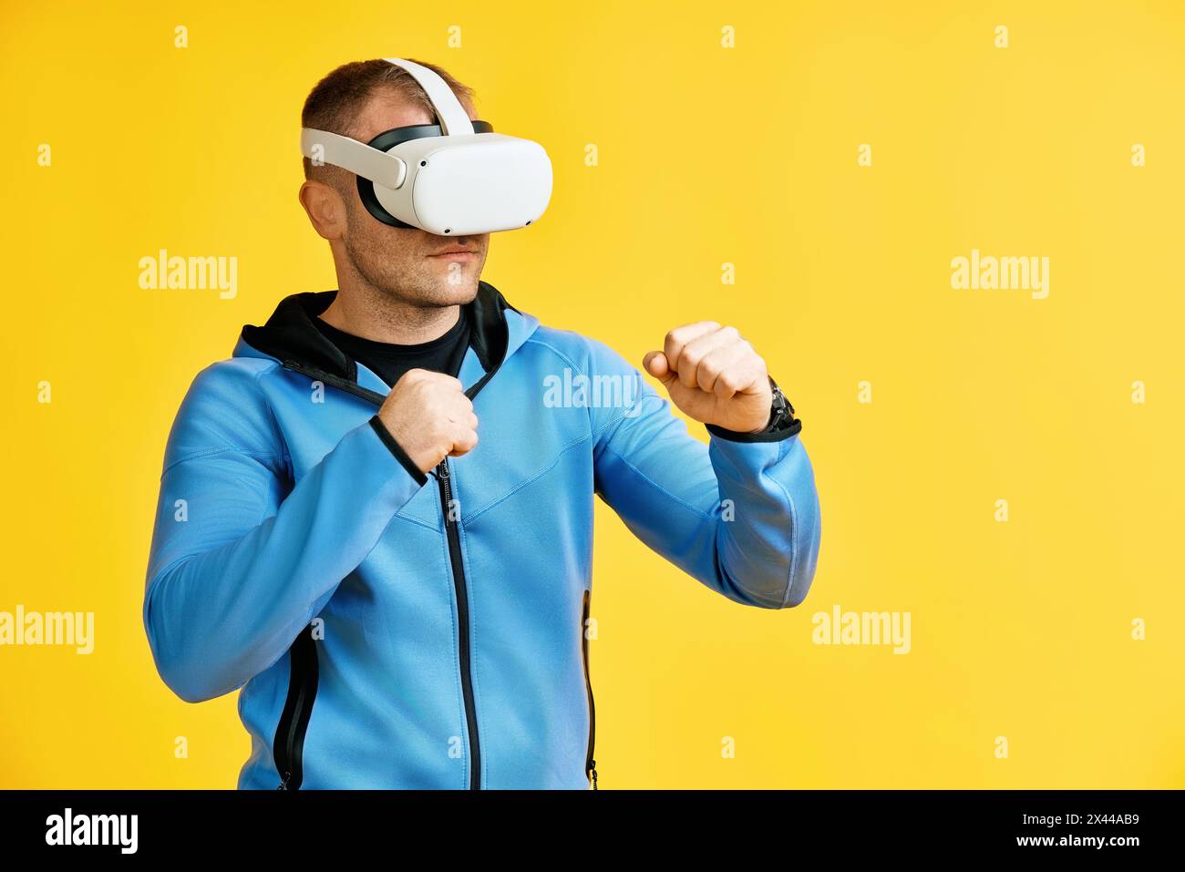 Homme portant des lunettes de réalité virtuelle faisant de la boxe d'ombre sur fond jaune Banque D'Images