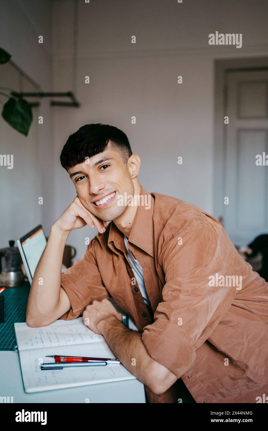 Portrait de souriant freelance masculine se penchant sur le coude au bureau dans le bureau à domicile Banque D'Images