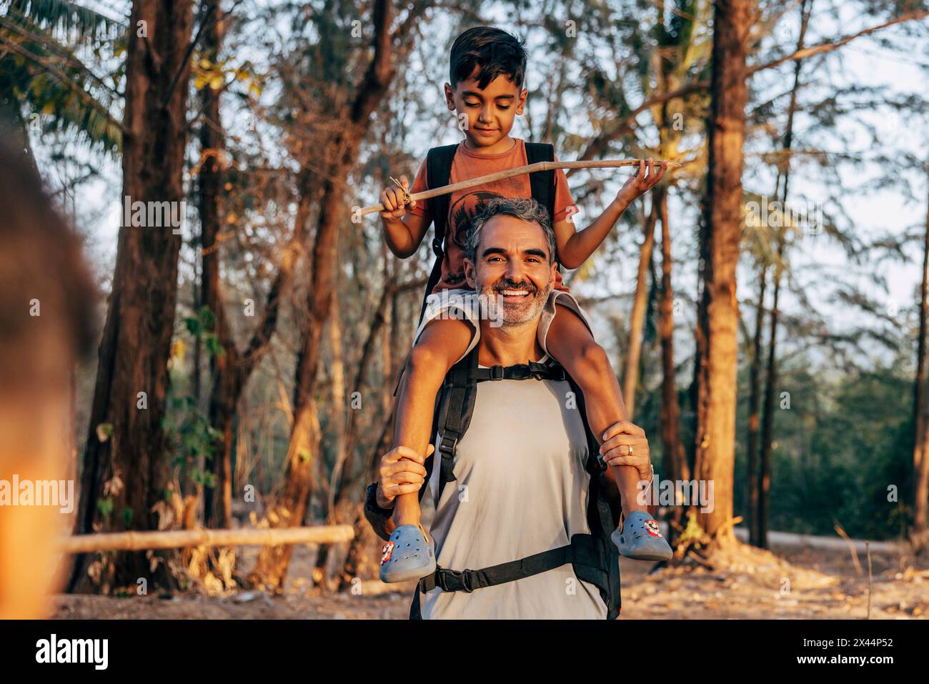 Portrait of happy father carrying son on shoulders in forest Banque D'Images
