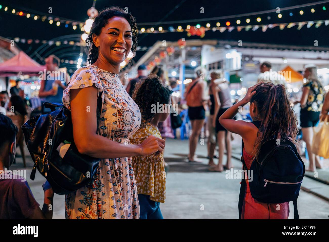 Vue de côté portrait de femme souriante explorant le marché alimentaire avec des enfants en vacances Banque D'Images