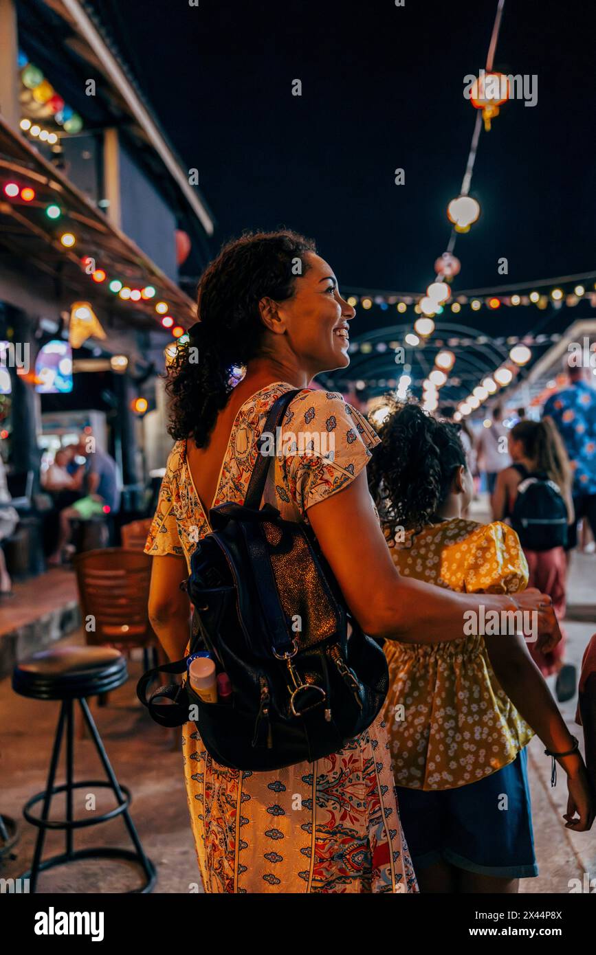 Femme souriante portant sac à dos et explorant le marché alimentaire avec sa fille en vacances Banque D'Images
