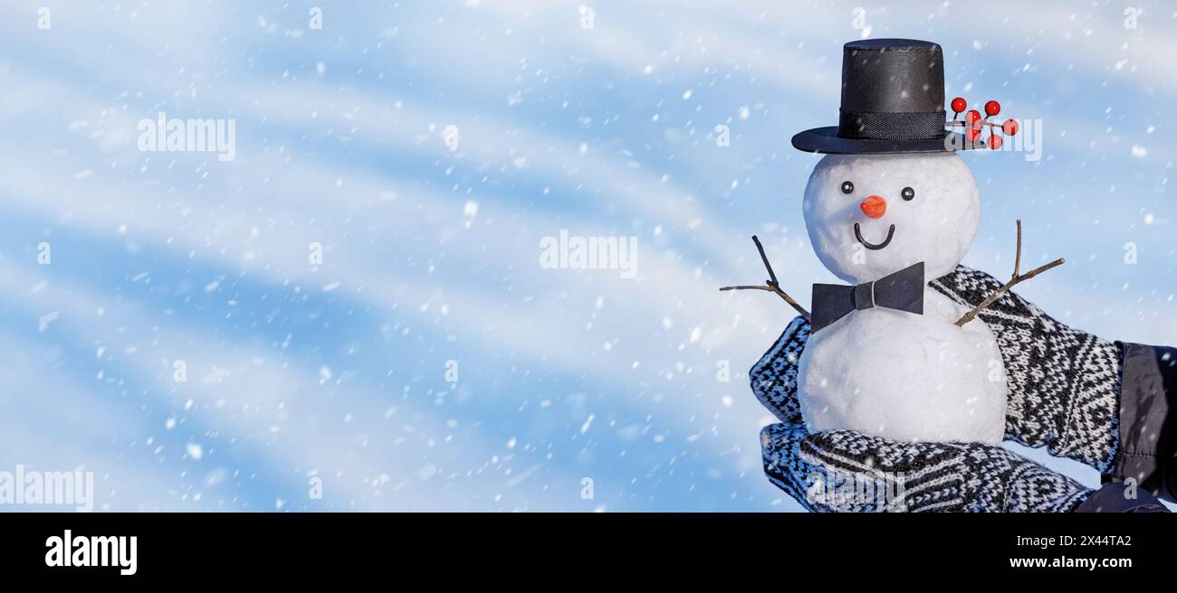 Bannière d'hiver de Noël - vue des mains tenant un petit bonhomme de neige. Fond de vacances avec espace de copie pour le texte Banque D'Images