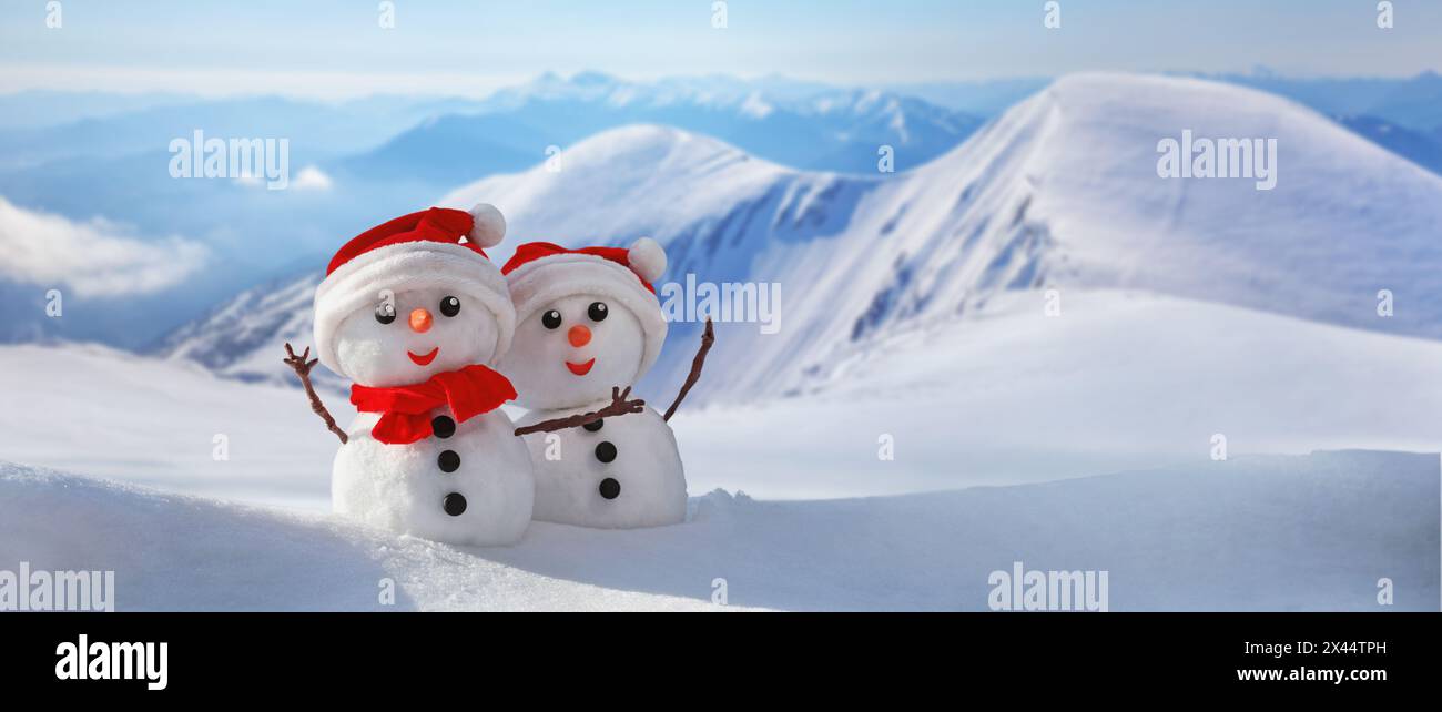 Bannière d'hiver de Noël avec un couple de bonhommes de neige dans un chapeau de père noël sur leurs têtes contre la toile de fond des montagnes enneigées. Arrière-plan congé avec copie sp Banque D'Images