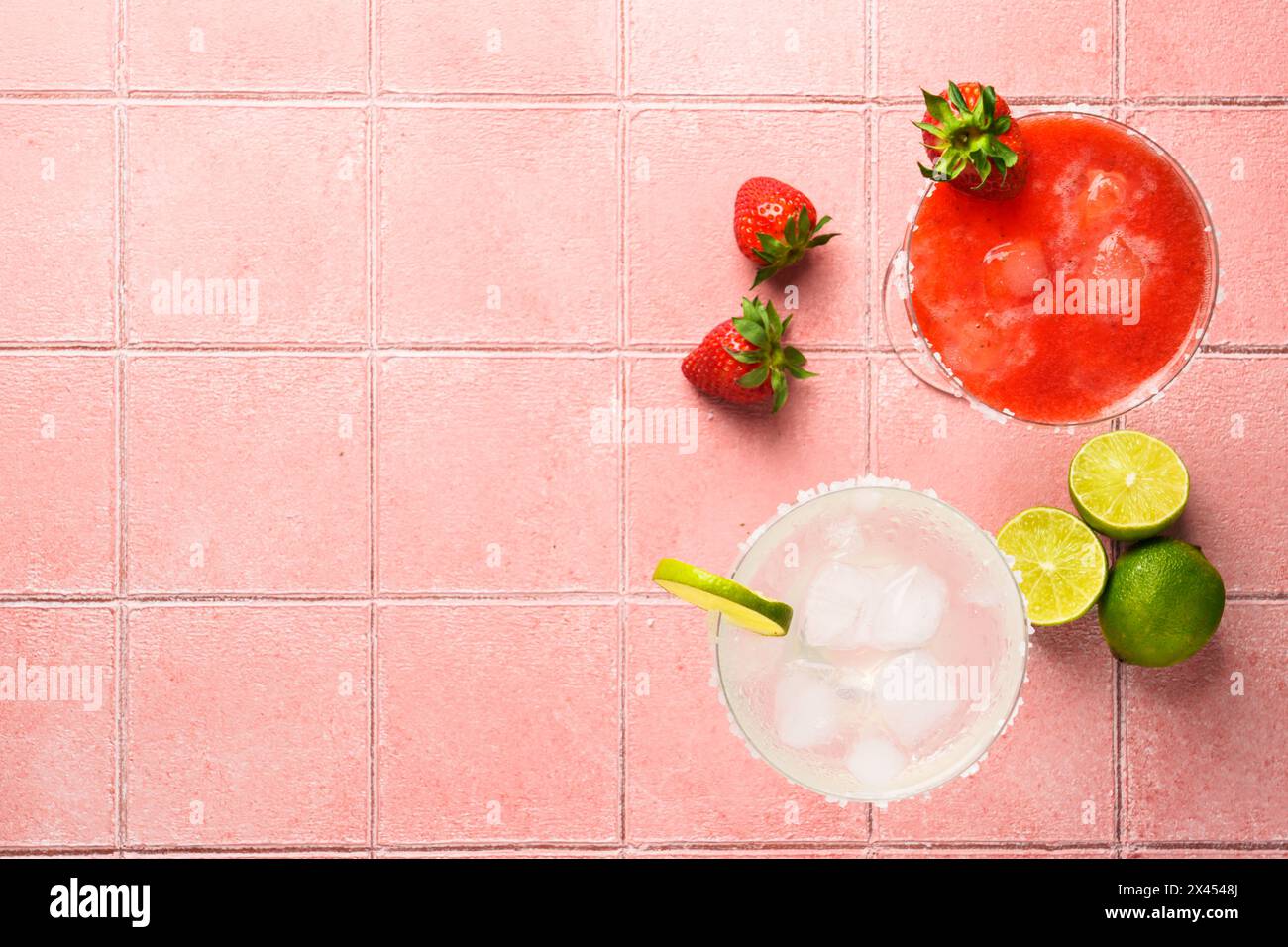 Margaritas classiques et à la fraise avec tequila et citron vert sur fond de couleur. Vue de dessus sur tuile rose. Banque D'Images