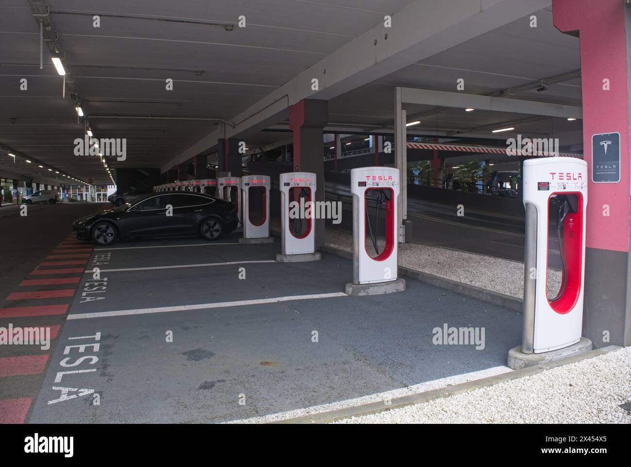 Brest, France - 7 avril 2024 : une photo statique d'un solide Tesla Model 3 noir à double moteur se chargeant au superchager V3 de Brest dans un jour de printemps pluvieux. Séléc Banque D'Images