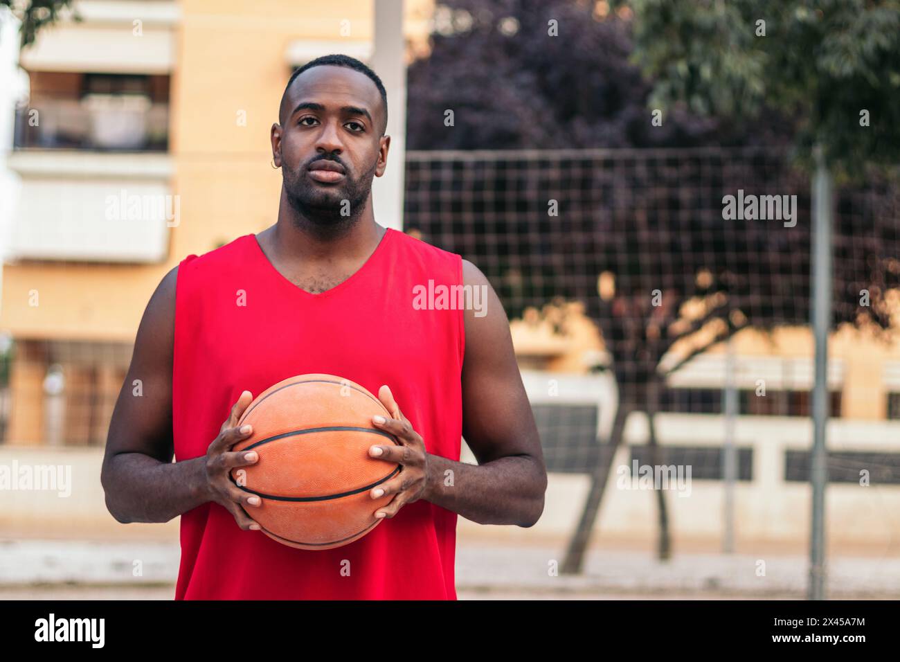 Portrait d'un joueur de basket-ball masculin sur le terrain. Il tient le basket avec confiance Banque D'Images