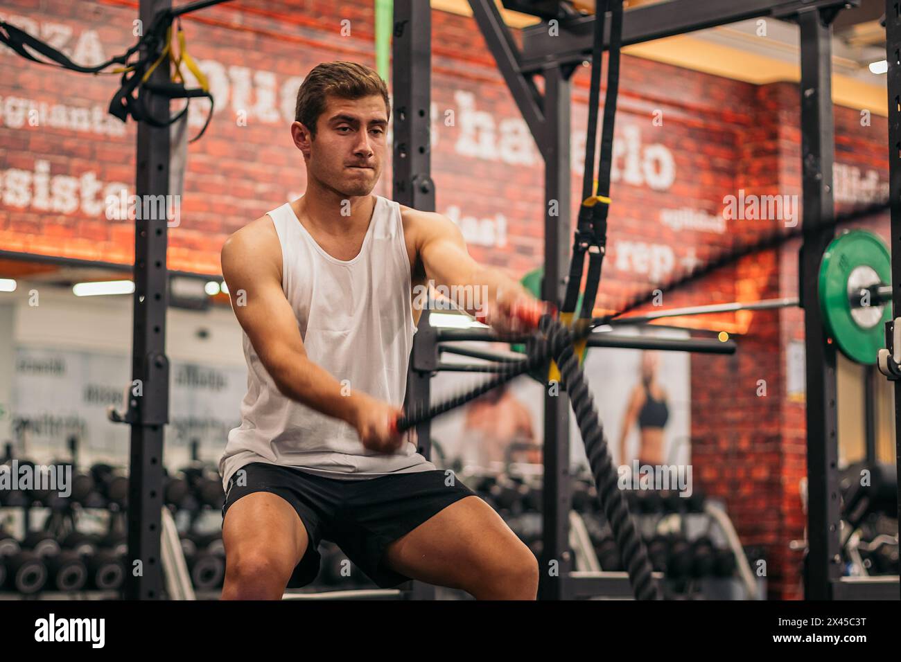 homme athlète s'entraîner avec les cordes dans une salle de gym Banque D'Images
