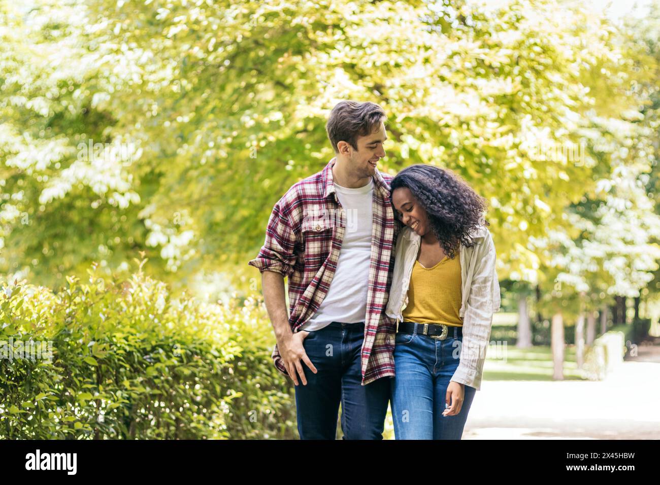 Heureux couple multiracial jeune d'homme caucasien et femme afro-américaine ayant une promenade romantique dans le parc Banque D'Images