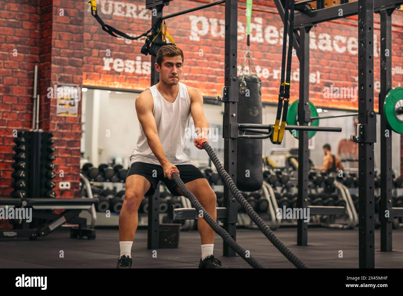 homme athlète s'entraîner avec les cordes dans une salle de gym Banque D'Images