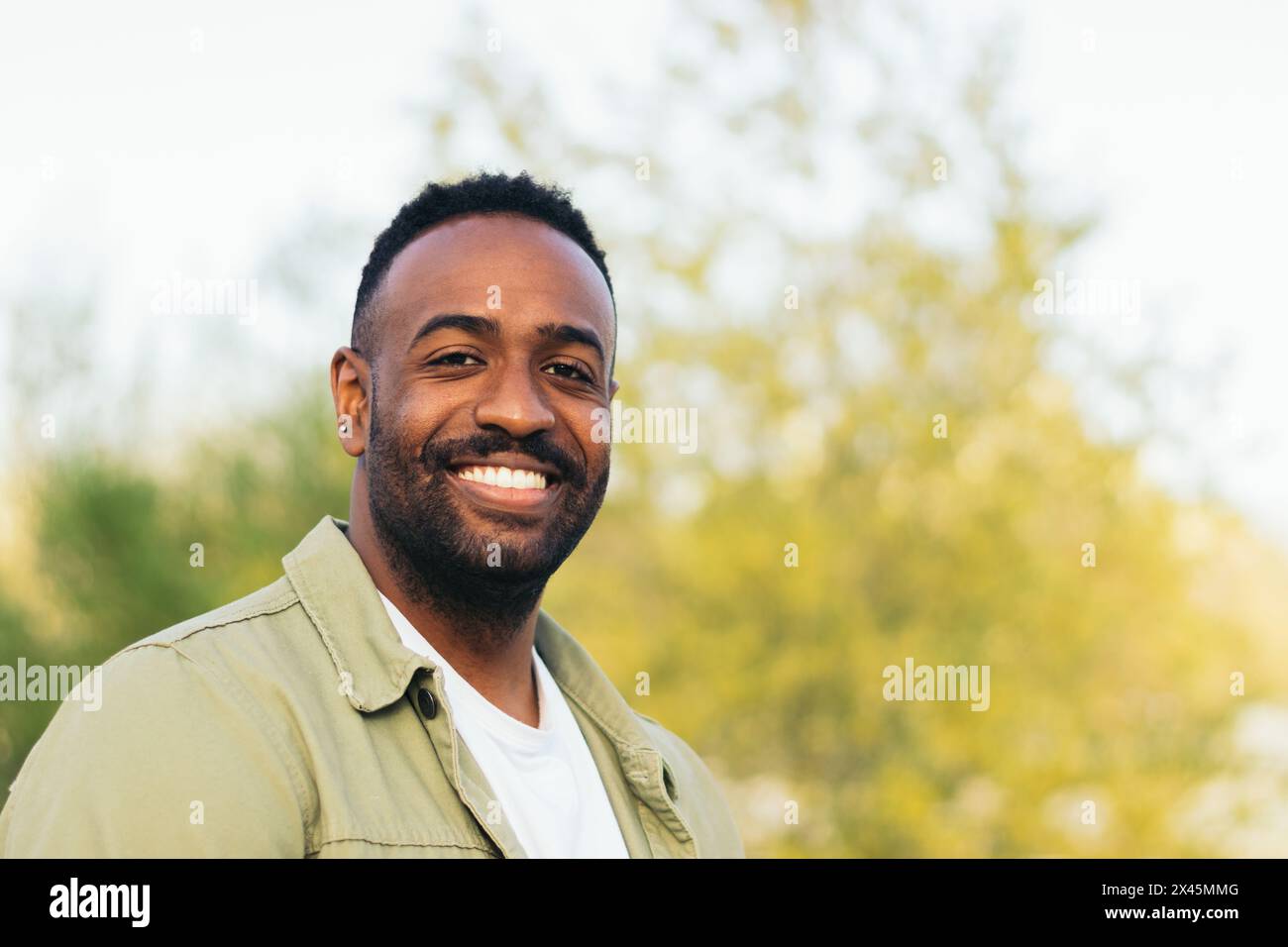 portrait de jeune homme afro-américain souriant dans un parc Banque D'Images
