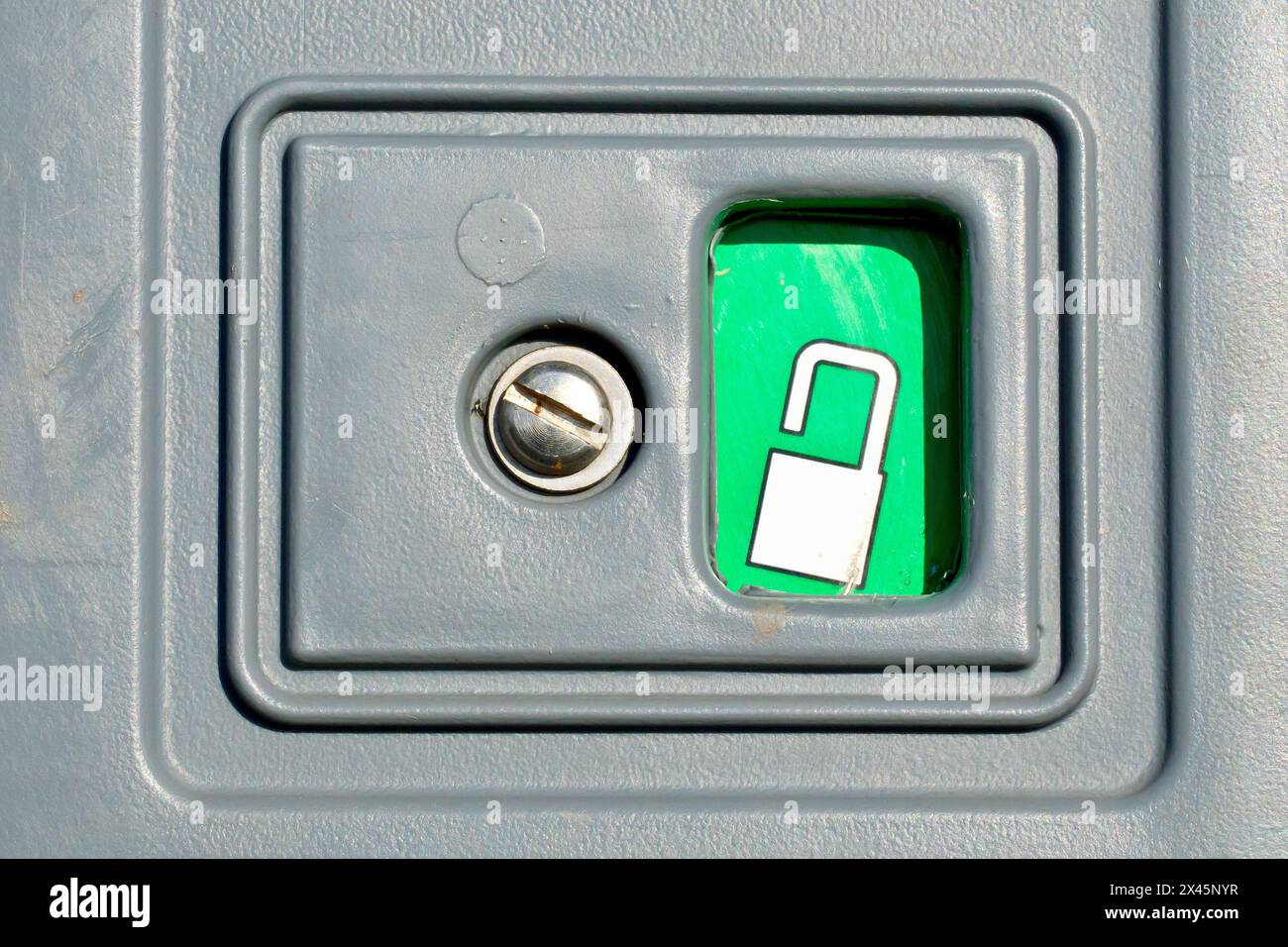 Gros plan de la serrure sur une toilette portative montrant un cadenas ouvert sur un fond vert pour indiquer que la porte est déverrouillée et que l'unité est vacante. Banque D'Images