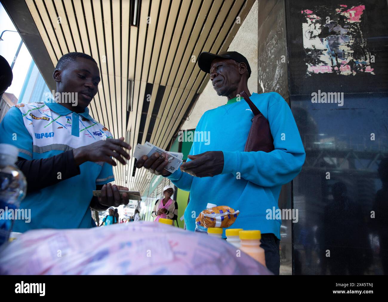 Harare, Zimbabwe. 30 avril 2024. Un homme utilise de nouvelles devises Zimbabwe Gold billets pour acheter des boissons devant une banque à Harare, Zimbabwe, le 30 avril 2024. Les nouvelles pièces et billets Zig du Zimbabwe ont commencé à circuler mardi, marquant une étape importante dans la réforme monétaire du pays visant à freiner l'inflation trois semaines seulement après que la forme électronique de la monnaie a commencé à être commercialisée. Crédit : Shaun Jusa/Xinhua/Alamy Live News Banque D'Images