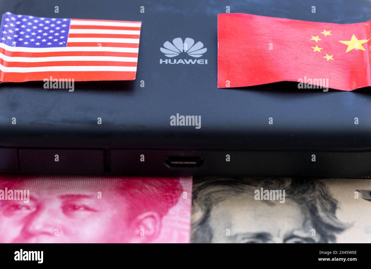 Londres. UK- 04.26.2024. Un concept technologique politique et économique. Le logo a sur un appareil Huawei au milieu du drapeau national chinois et américain et b Banque D'Images