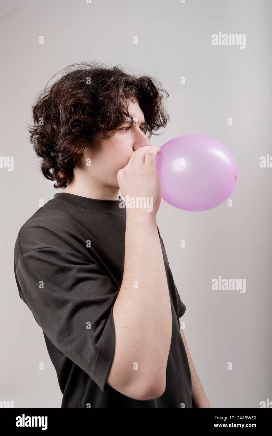 garçon caucasien gonflant un ballon en studio Banque D'Images