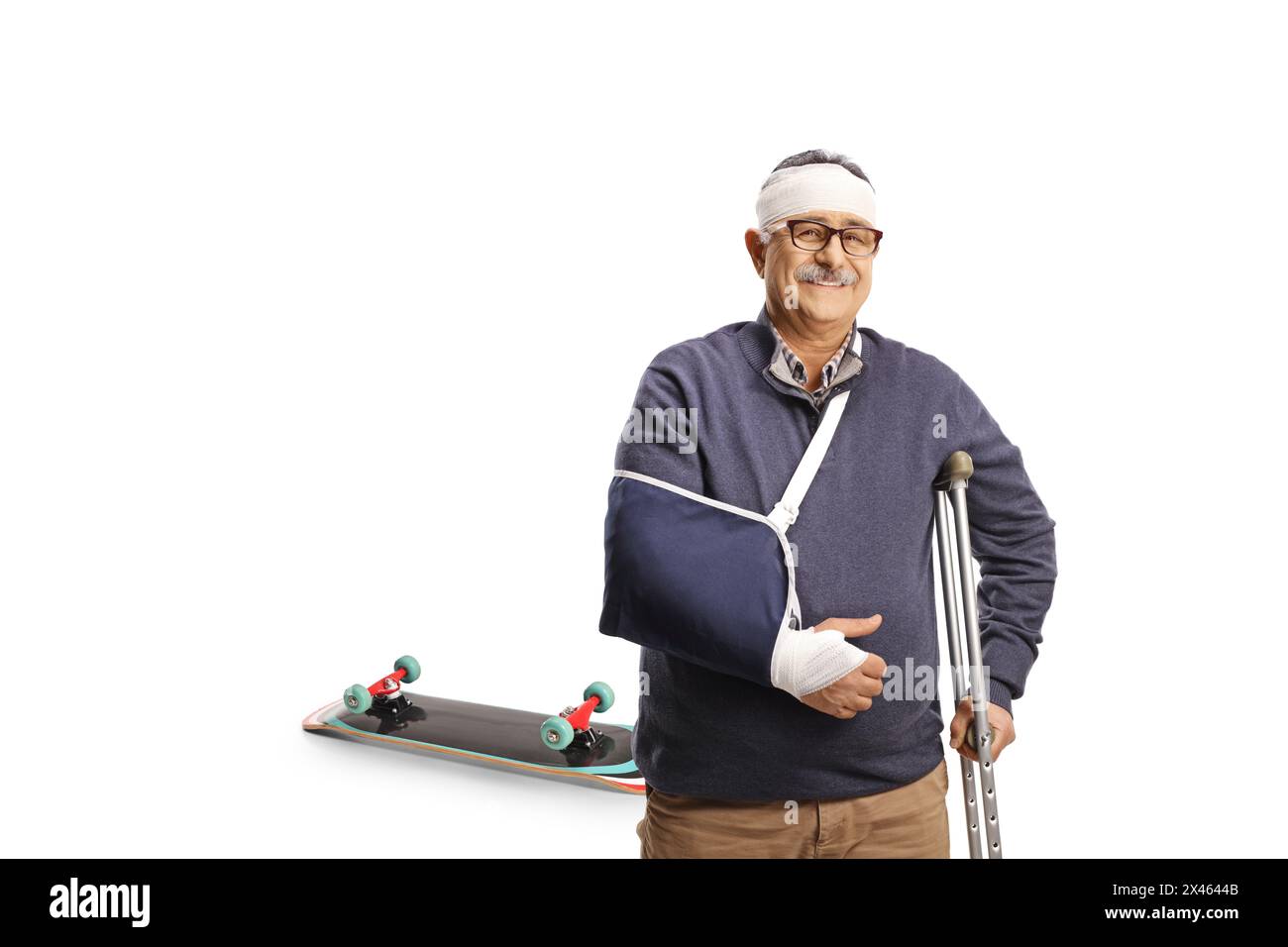 Homme mûr avec un bras cassé et un bandage sur la tête appuyé sur une béquille blessée d'une promenade en skateboard isolé sur fond blanc Banque D'Images