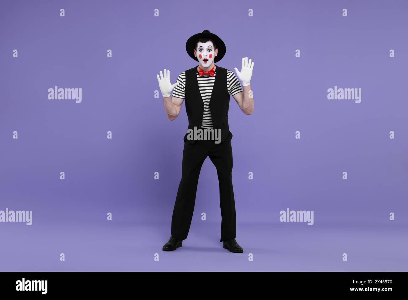 MIME artiste faisant visage choqué sur fond violet Banque D'Images