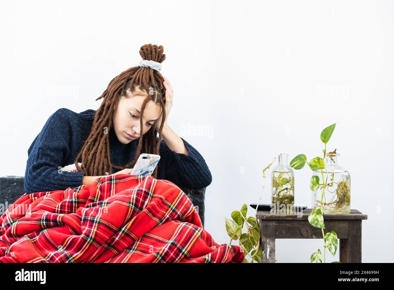 Femme avec des dreadlocks utilisant un téléphone portable t home Banque D'Images