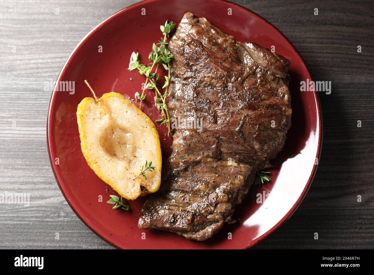Délicieuse viande de bœuf rôtie, poire caramélisée et thym sur table en bois gris, vue de dessus Banque D'Images
