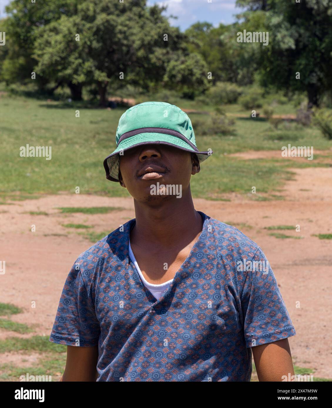 jeune homme africain avec un chapeau tiré sur les yeux, village africain, dans la brousse, protection solaire Banque D'Images