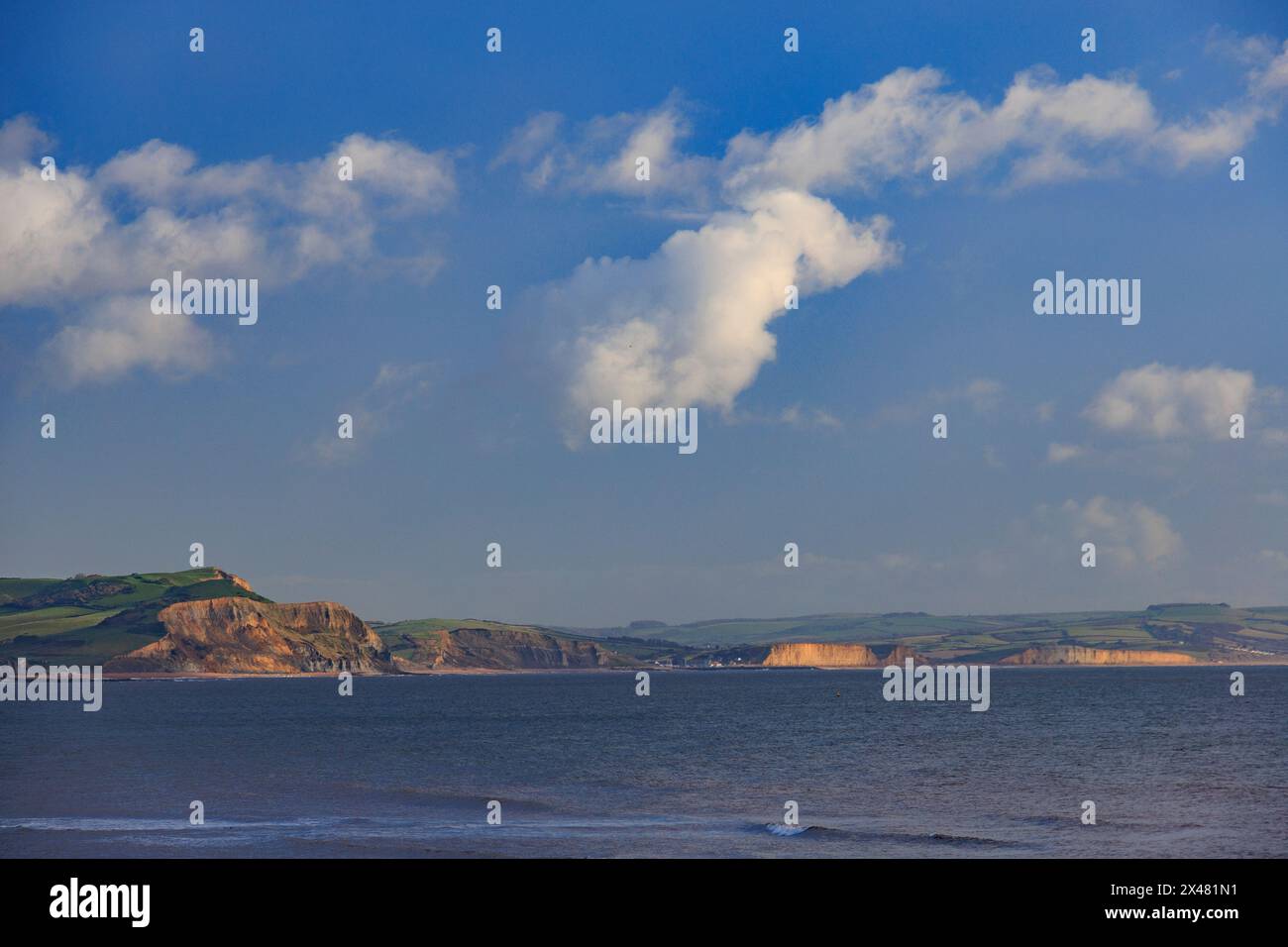 Vue à travers la baie de Lyme depuis Lyme Regis vers les falaises de West Bay sur la côte jurassique éclairée par le soleil d'hiver, Dorset, Angleterre, Royaume-Uni Banque D'Images