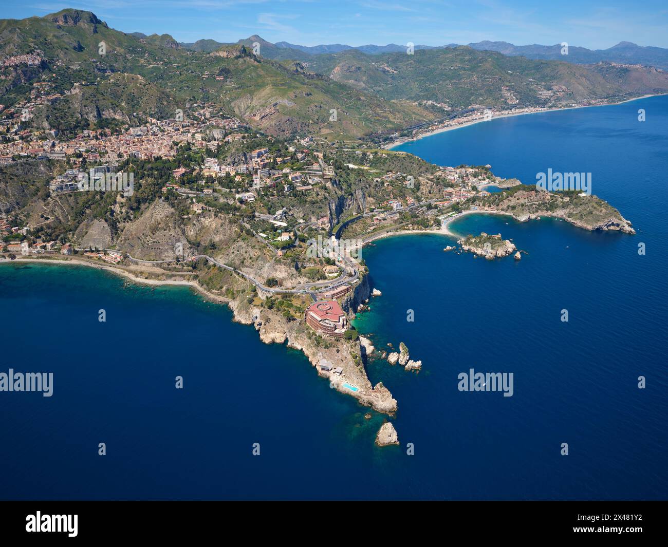 VUE AÉRIENNE. Les promontoires rocheux de Taormina se projetant dans la mer Ionienne. Ville métropolitaine de Messine, Sicile, Italie. Banque D'Images