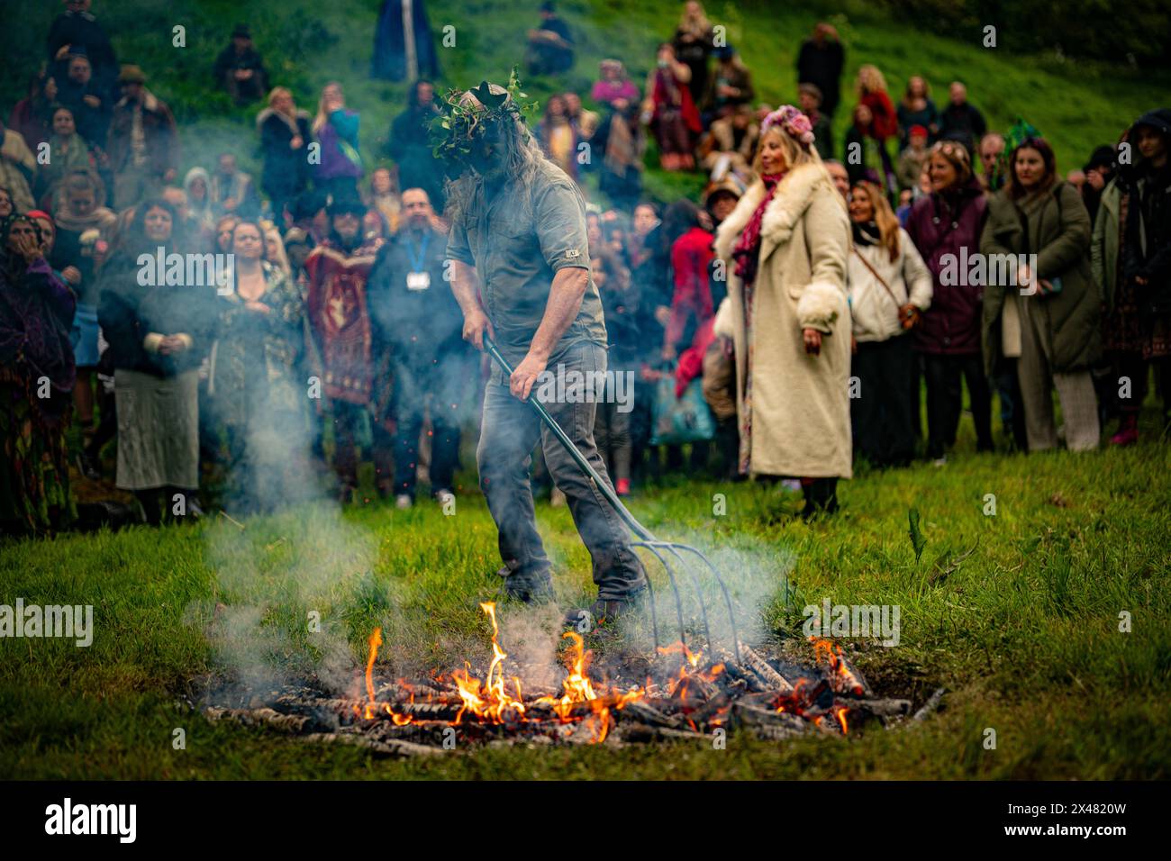 Des cendres chaudes et du bois sont raclés sur le feu avant de sauter le feu lors des célébrations de Beltane à Glastonbury Chalice Well, où ils observent une interprétation moderne de l'ancien rite païen celtique de fertilité du printemps. Date de la photo : mercredi 1er mai 2024. Banque D'Images