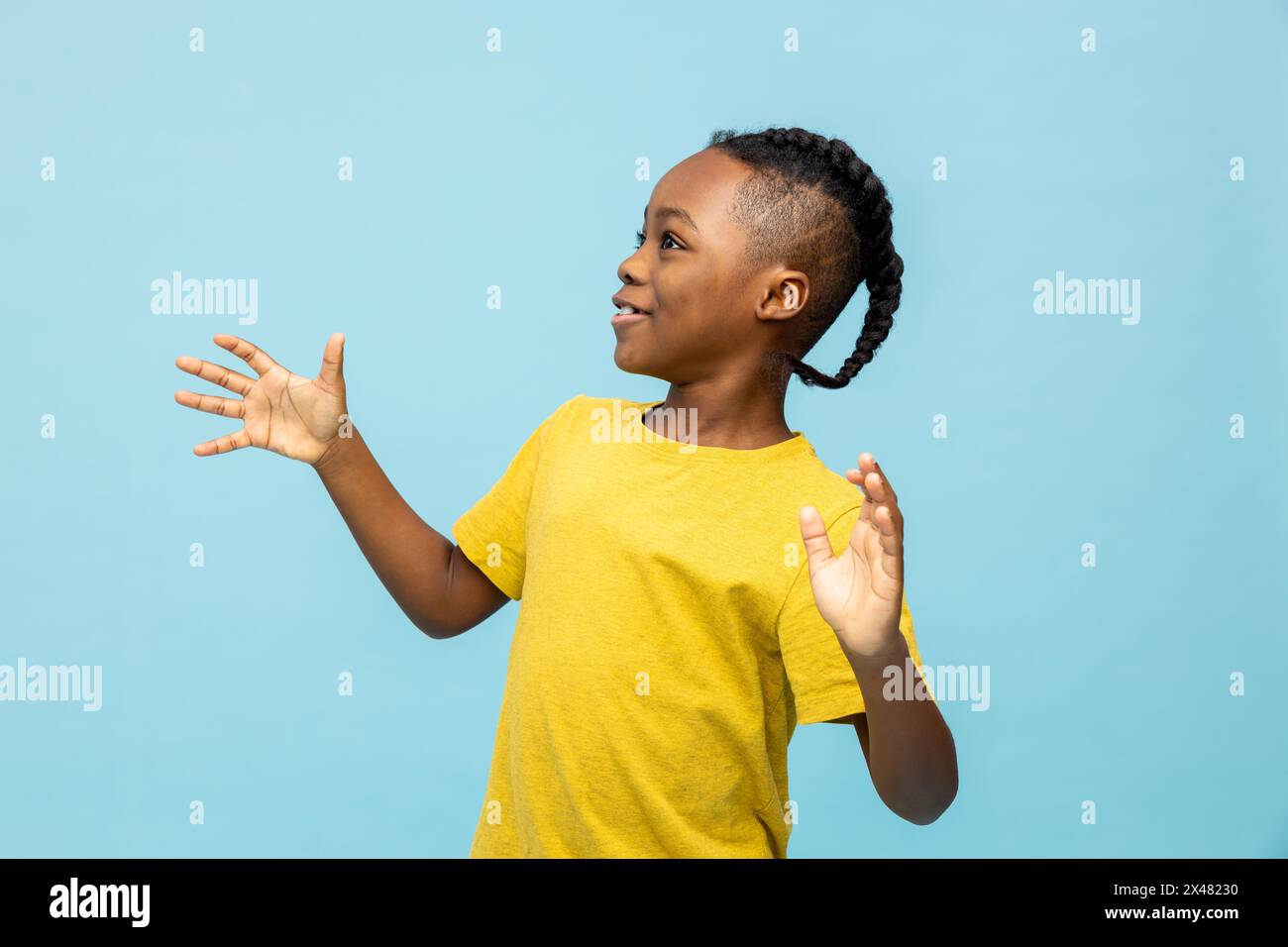 Garçon à la peau foncée dans un tshirt jaune regardant excité et heureux Banque D'Images