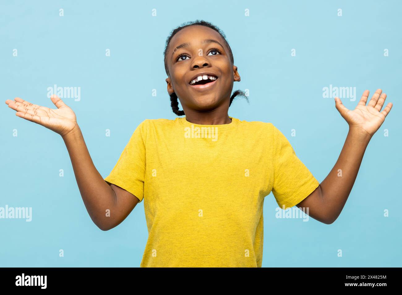 Garçon à la peau foncée dans un tshirt jaune regardant excité et heureux Banque D'Images
