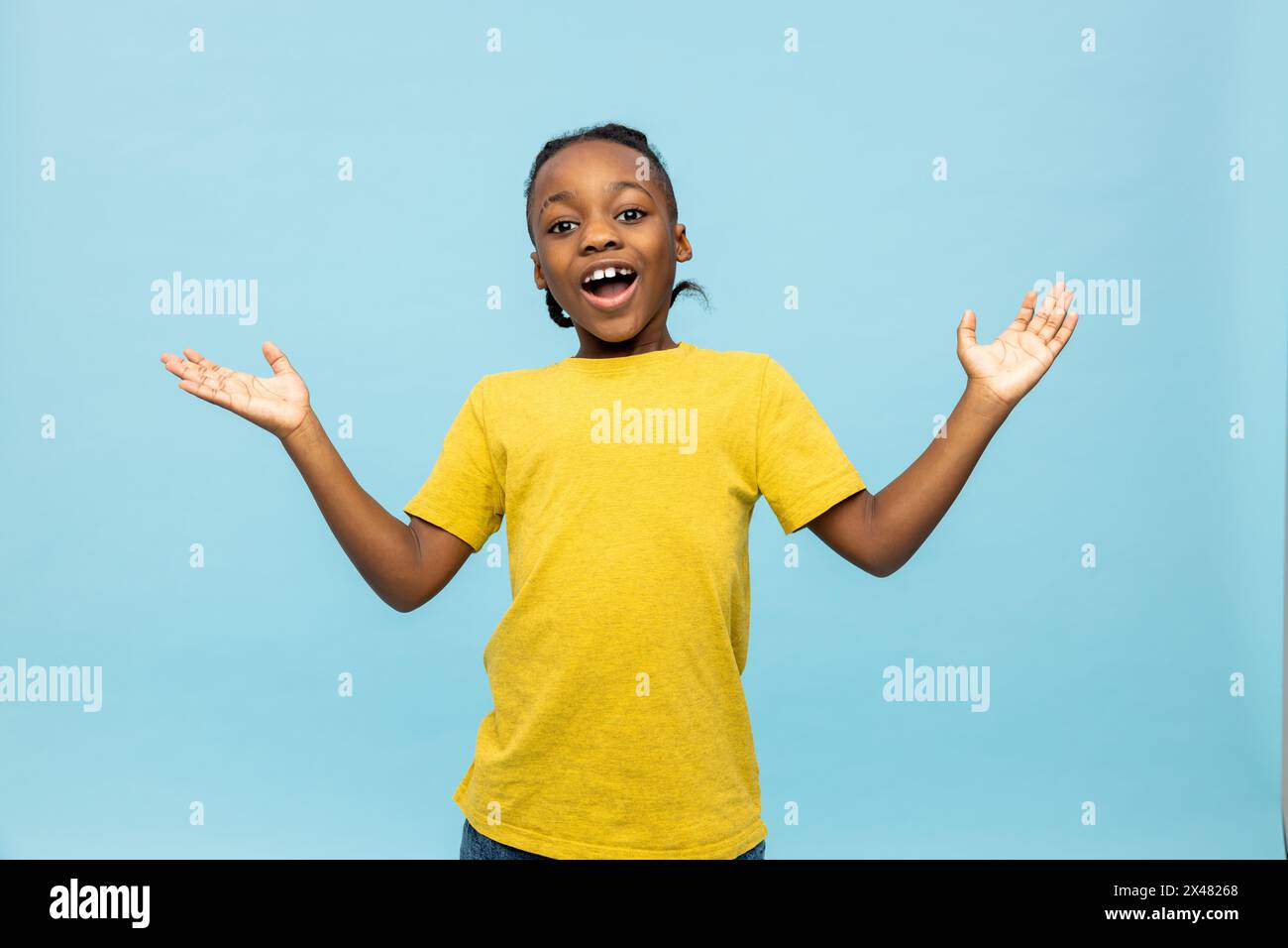 Garçon à la peau foncée dans un tshirt jaune regardant excité et heureux Banque D'Images