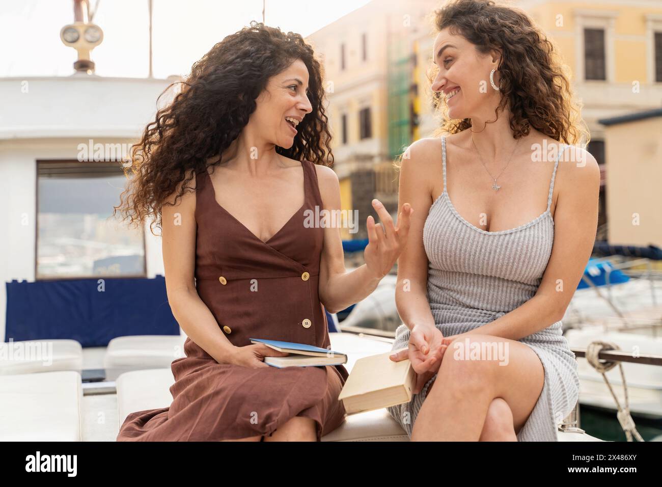 Deux femmes - rire et parler sur yacht - atmosphère détendue et joyeuse, cadre urbain - bonheur, amitié, loisirs. Banque D'Images