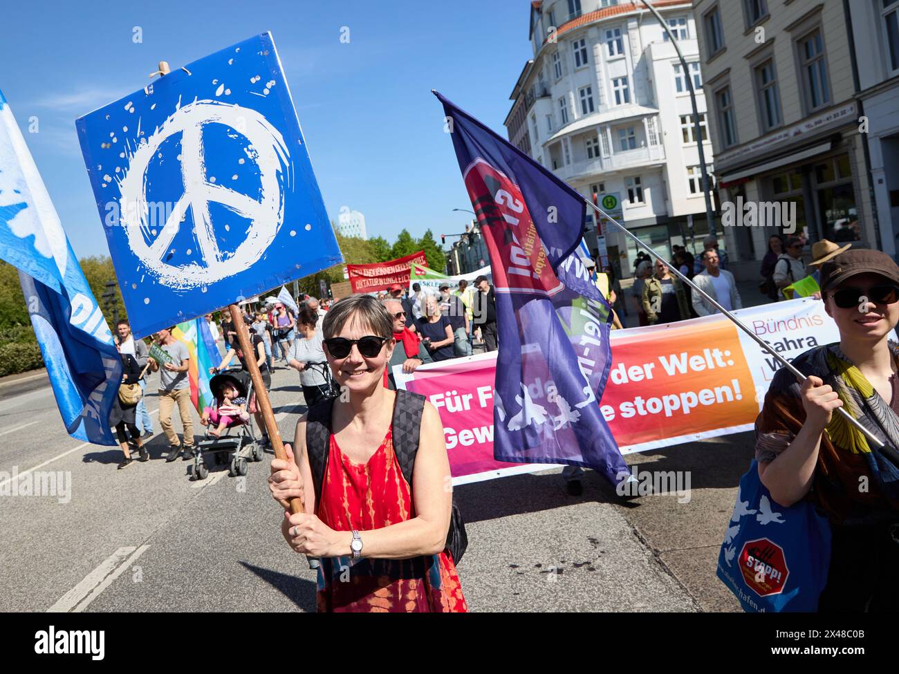 Hambourg, Allemagne. 01 mai 2024. Un démonstrateur tient une bannière avec le symbole de la paix sur Max-Brauer-Allee. Sous le slogan "plus de salaire, plus de temps libre, plus de sécurité", la Confédération allemande des syndicats (DGB) et ses syndicats membres ont appelé les gens à participer aux activités du 1er mai 2024, "Fête du travail". Crédit : Georg Wendt/dpa/Alamy Live News Banque D'Images