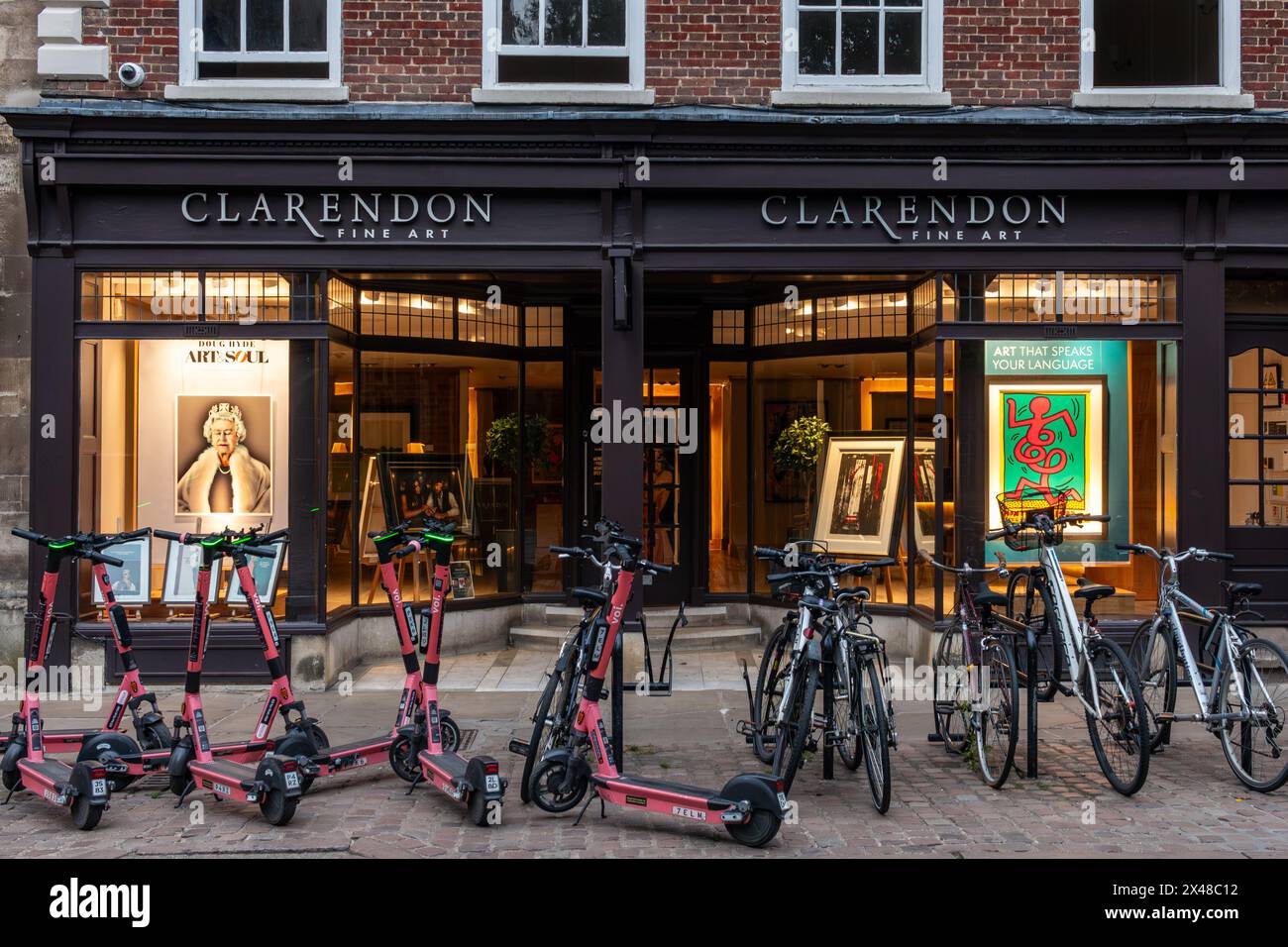 Vue en soirée sur la galerie d'art Clarendon avec scooters électriques et vélos garés à l'extérieur. Un grand portrait de la reine Elizabeth II est à l'intérieur. Banque D'Images