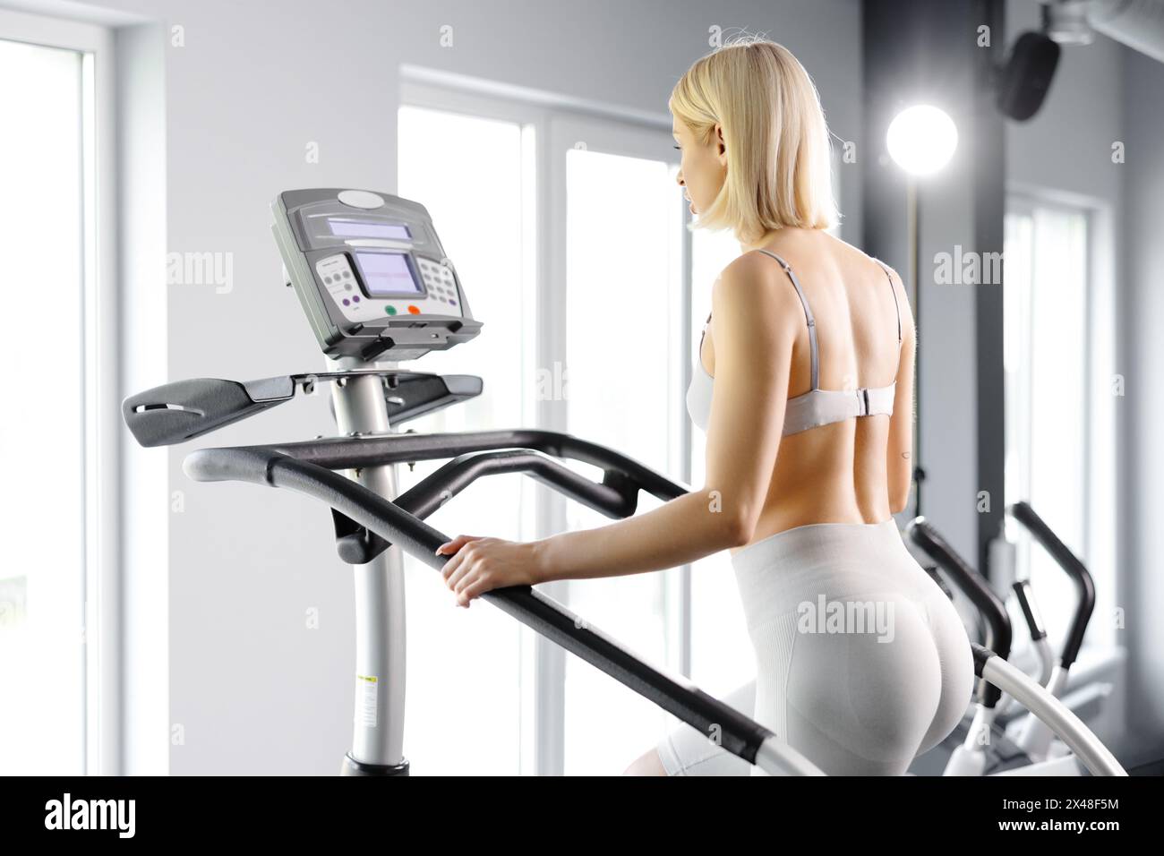 Jeune femme en sportswear s'exerçant à la salle de gym. Elle s'entraîne sur simulateur d'escalier. Banque D'Images