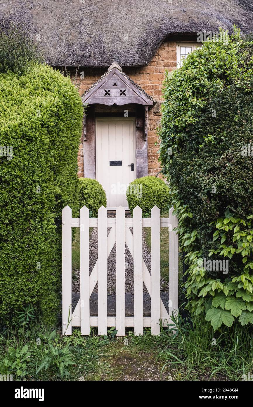 Porte de piquetage blanche dans le cottage Cotswold dans le village endormi de Great Tew dans l'Oxfordshire. Banque D'Images