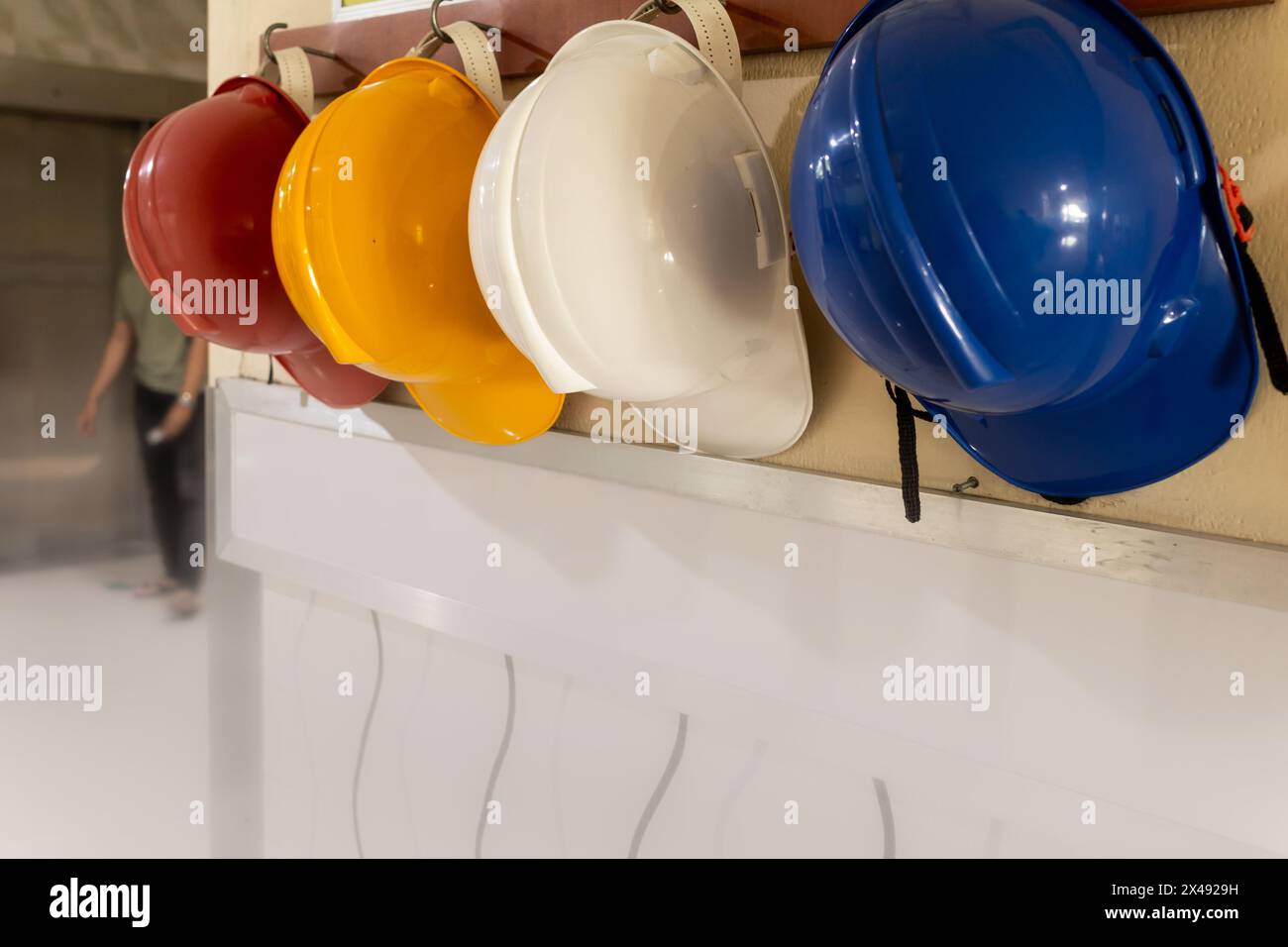 Casques de sécurité différenciés par la couleur rouge, jaune, blanc et bleu étant accrochés au mur de l'hôpital Banque D'Images