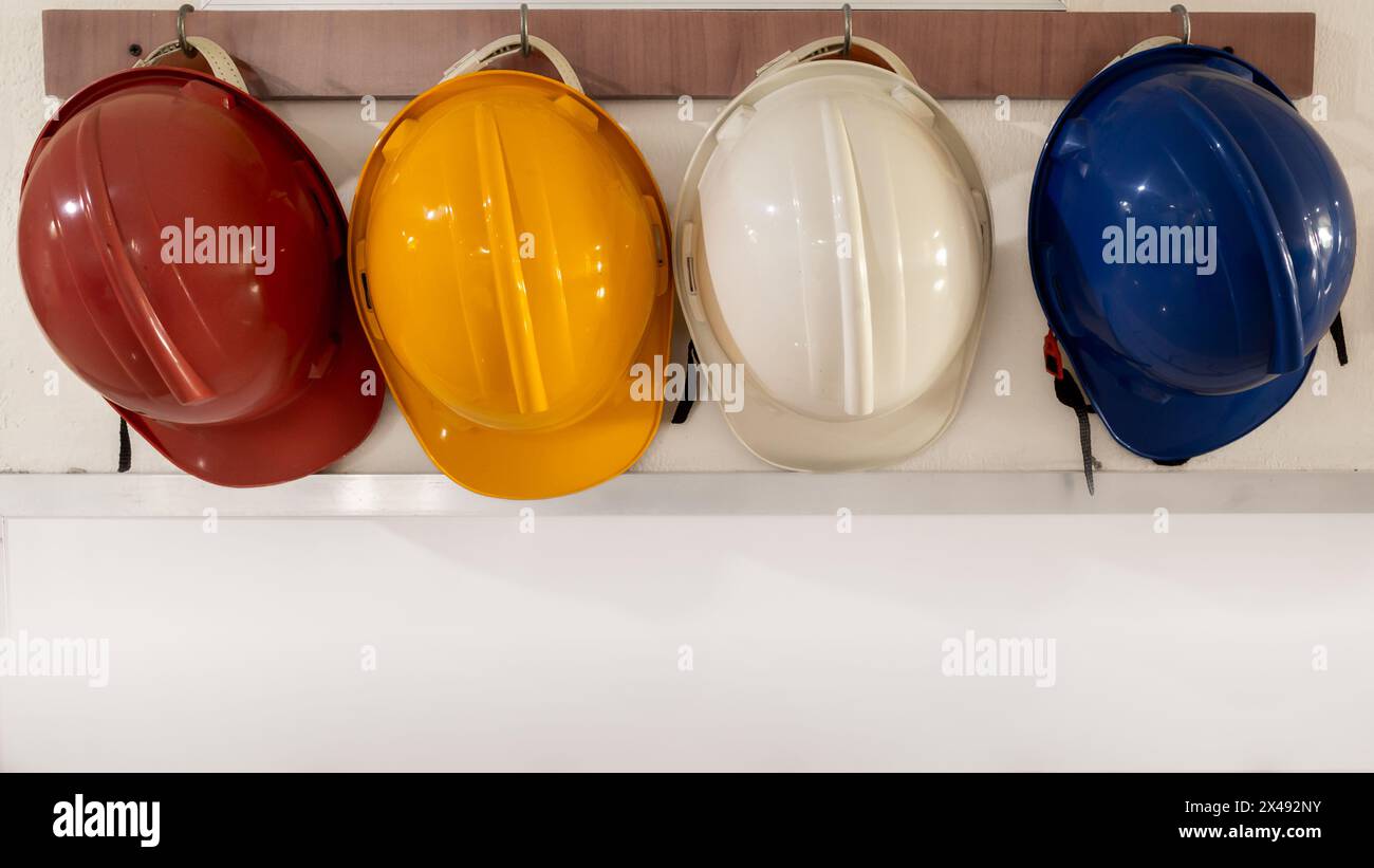 Casques de sécurité différenciés par la couleur rouge, jaune, blanc et bleu étant accrochés au mur de l'hôpital Banque D'Images