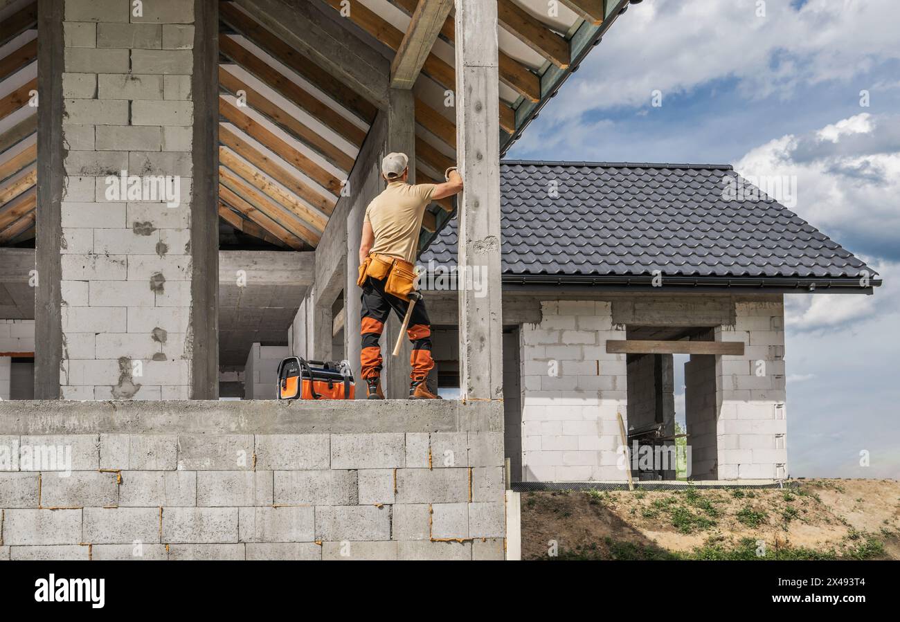 Ouvrier de chantier de construction caucasien et la maison de style européen de briques de béton nouvellement développée Banque D'Images