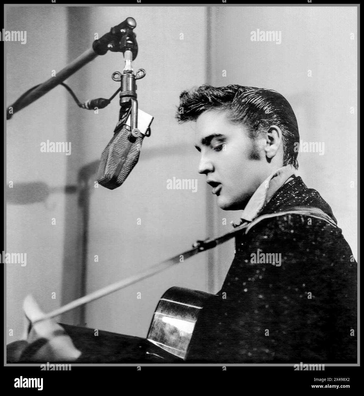ELVIS PRESLEY iconique pop star dans les années 1950 au début de sa carrière, chantant et jouant également de sa guitare dans un studio d'enregistrement avec microphone de l'époque. Hollywood USA Banque D'Images