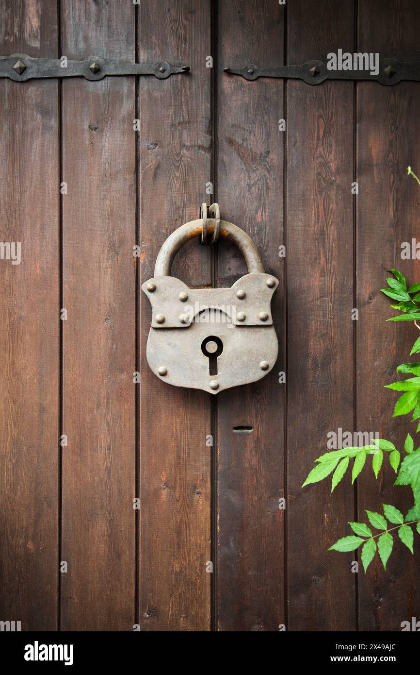 Vieux cadenas rouillé sur une porte en bois. Plan vertical . Porte en bois avec grande serrure en fer à charnières dans le village Banque D'Images