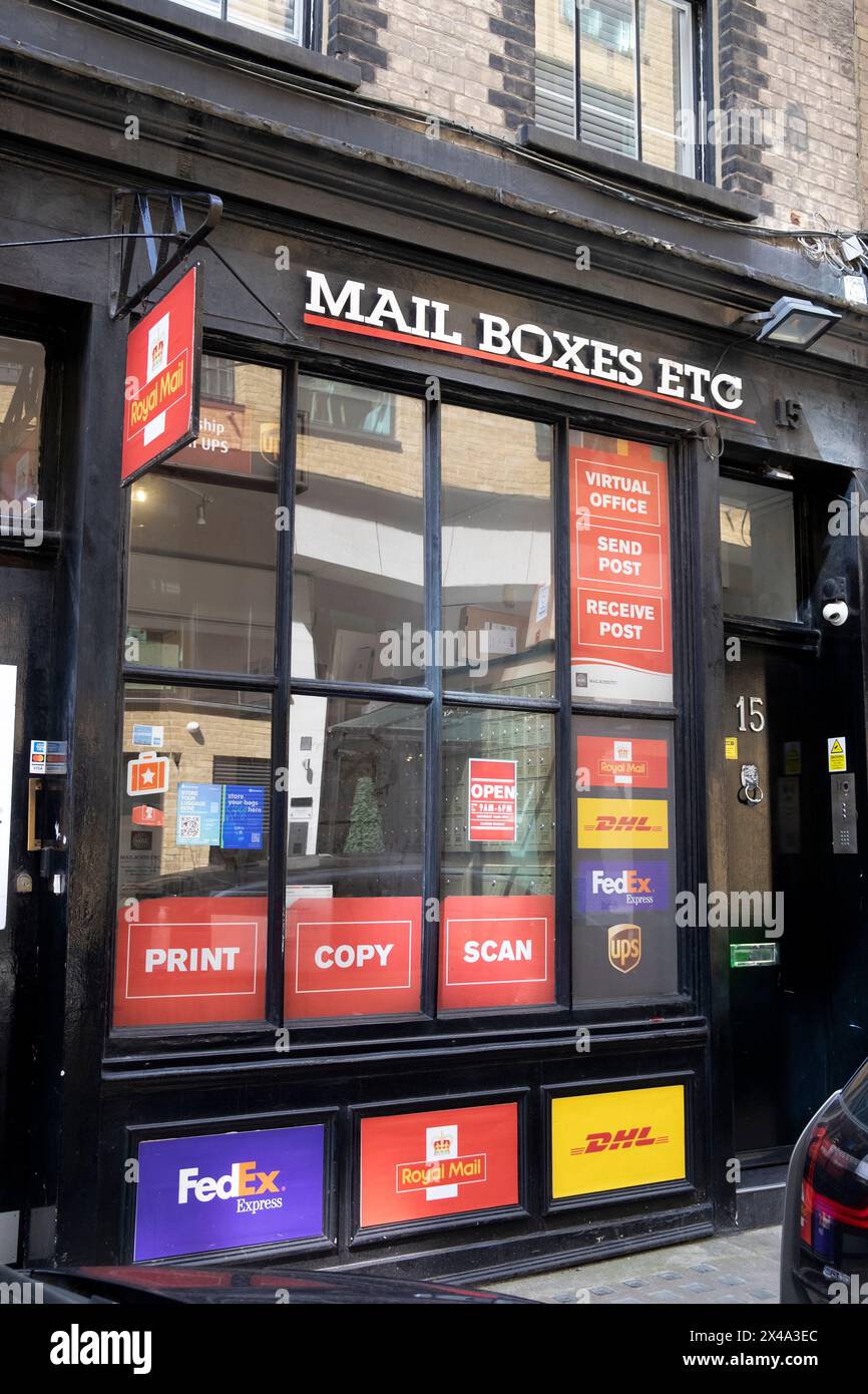 Vue extérieure avant des boîtes aux lettres etc petit magasin Fedex, Royal mail, DHL signes de service dans la fenêtre Soho Londres Angleterre Royaume-Uni KATHY DEWITT Banque D'Images