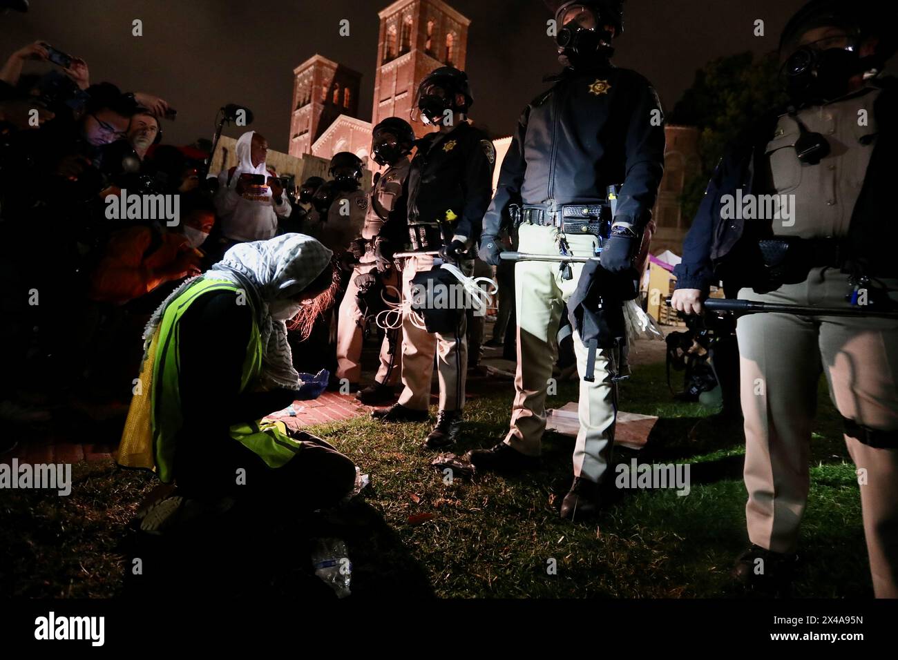 (240501) -- LOS ANGELES, 1er mai 2024 (Xinhua) -- Un manifestant pro-palestinien s'agenouille devant des policiers devant un campement de tentes en soutien aux Palestiniens près de Royce Hall de l'Université de Californie, Los Angeles (UCLA), à Los Angeles, Californie, États-Unis, le 1er mai 2024. L’Université de Californie à Los Angeles (UCLA), l’une des meilleures universités publiques des États-Unis, a annulé tous les cours pour mercredi après une nuit de violents affrontements sur le campus au sujet du conflit israélo-palestinien en cours à Gaza. (Xinhua) Banque D'Images