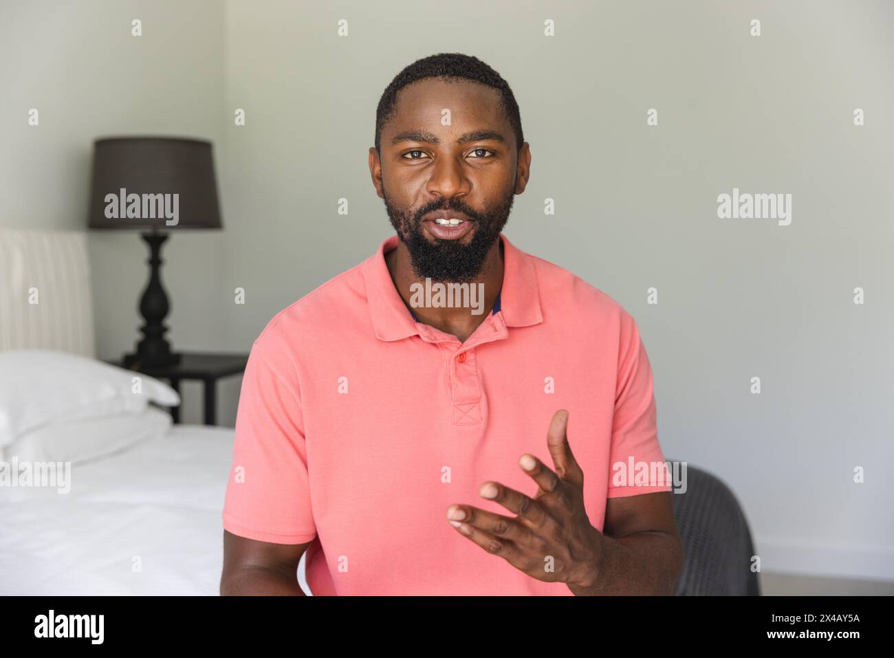 Homme afro-américain debout, parlant avec un geste de la main à la maison pendant un appel vidéo Banque D'Images
