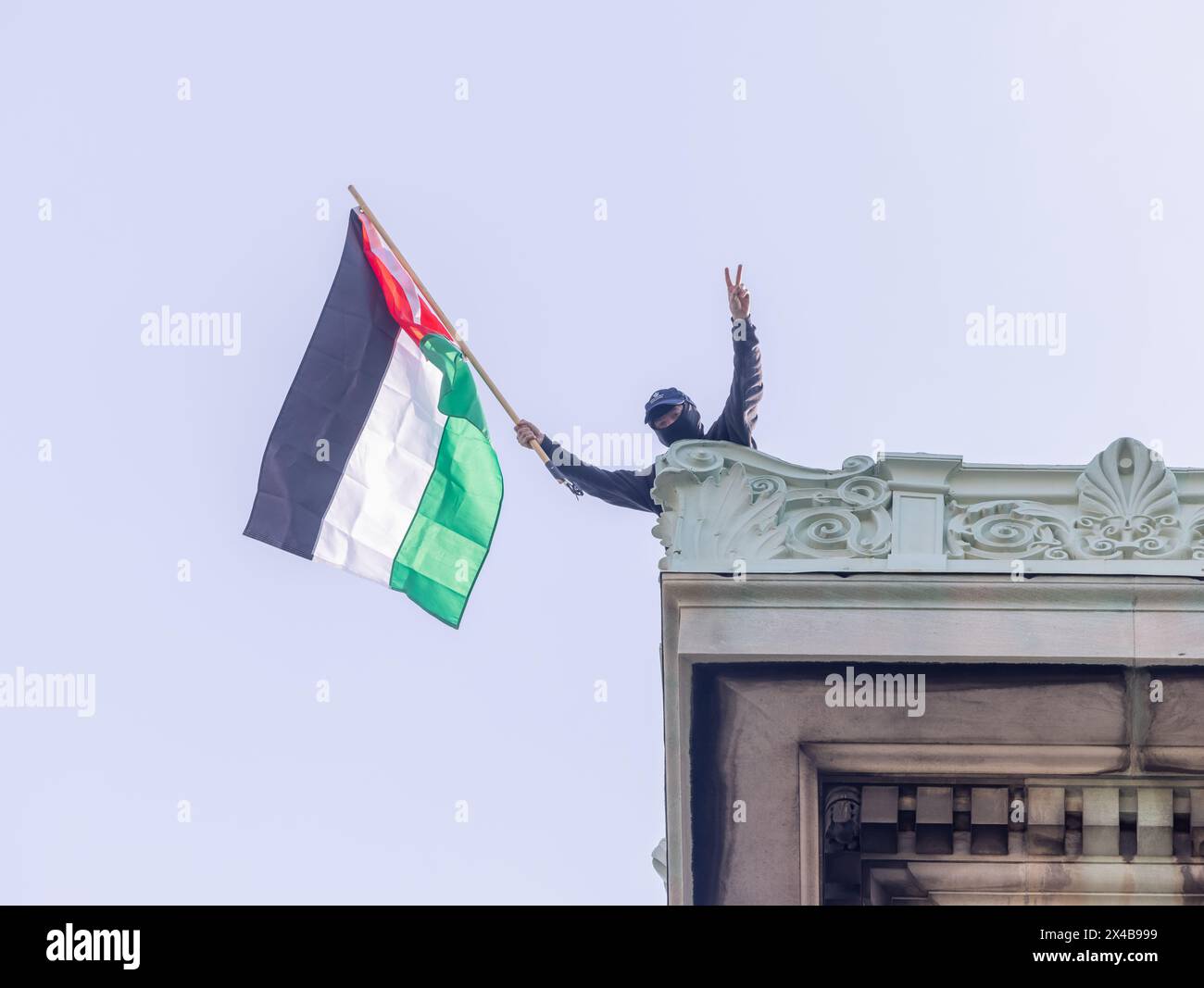 NEW YORK, NEW York – 30 avril 2024 : un manifestant agite un drapeau palestinien sur le toit du Hamilton Hall de l'Université Columbia à Manhattan. Banque D'Images
