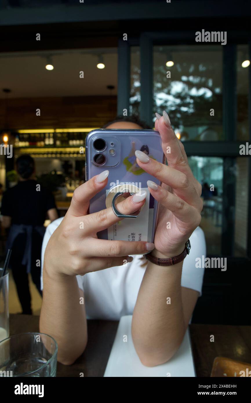 une photo de ma sœur (visage non révélé) tenant un téléphone (logo de la marque non révélé) Banque D'Images