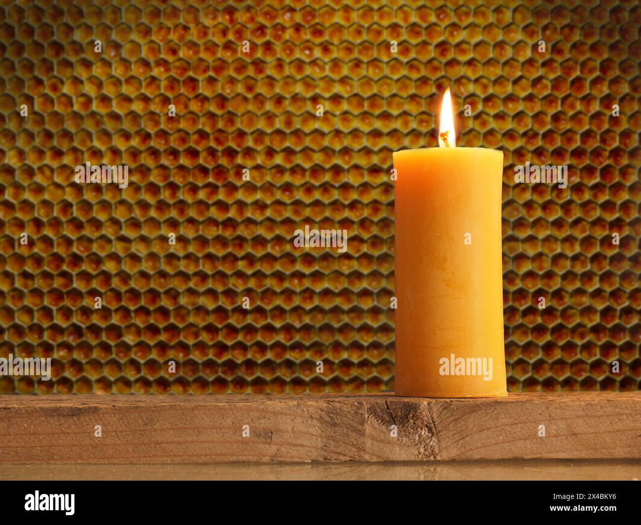 Bougie allumée en cire d'abeille devant un fond en nid d'abeille avec espace pour la DATE D'ENREGISTREMENT du texte NON INDIQUÉE Banque D'Images