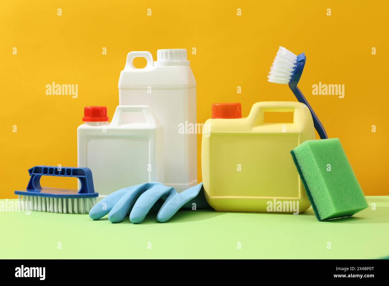 Kit de nettoyage pour différentes surfaces dans la cuisine, salle de bains et autres pièces. Bidons en plastique vierges affichés sur fond jaune avec des brosses bleues, RU Banque D'Images