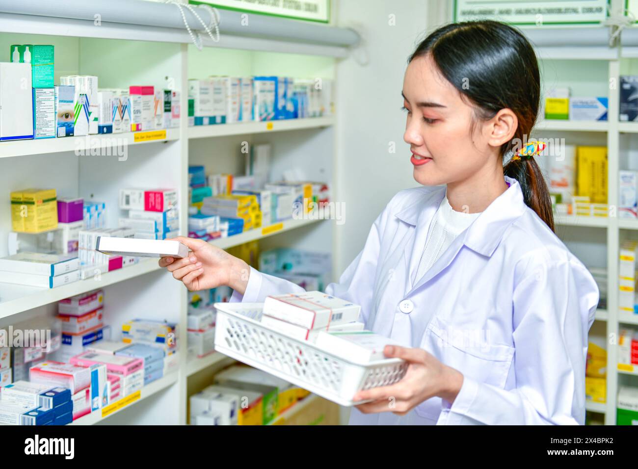 Pharmacien chimiste femme debout recharge les étagères avec de nouveaux stocks dans la pharmacie Banque D'Images