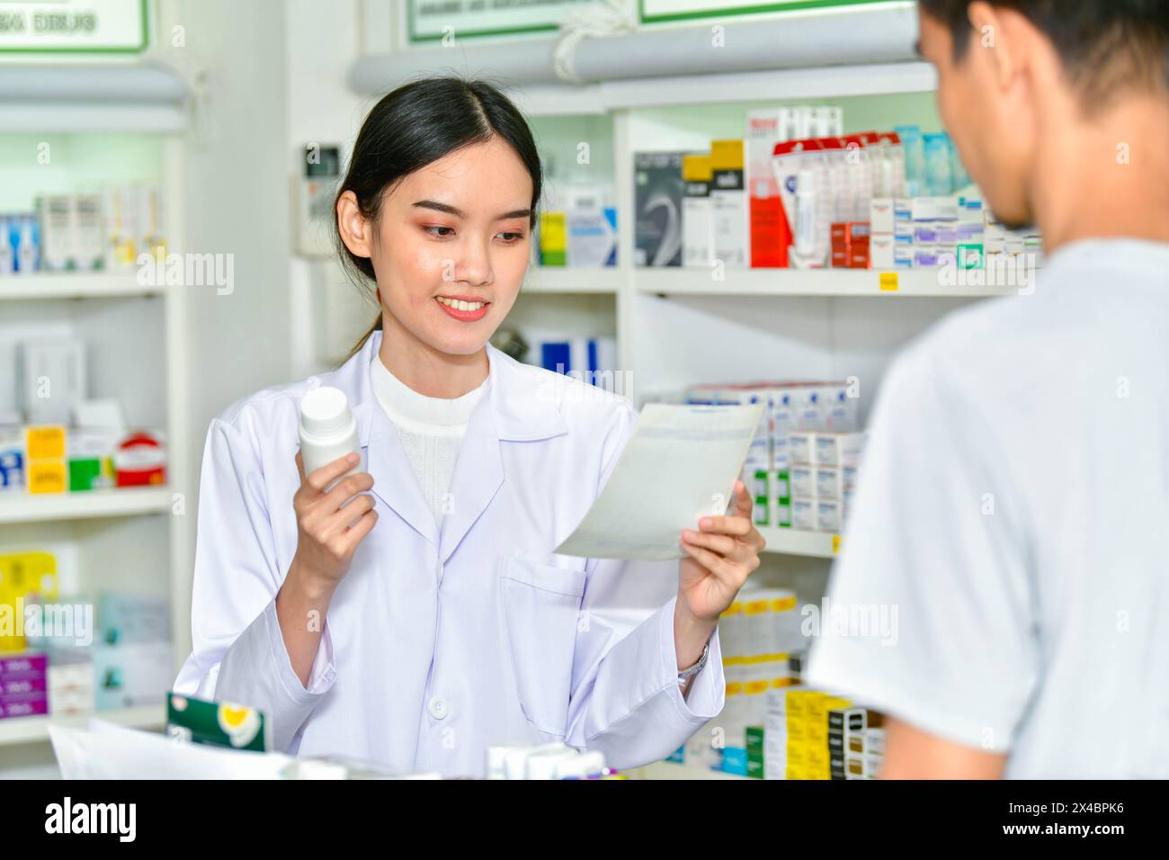 Femme pharmacienne tenant la boîte de médecine donnant des conseils au client dans le magasin de pharmacie Banque D'Images